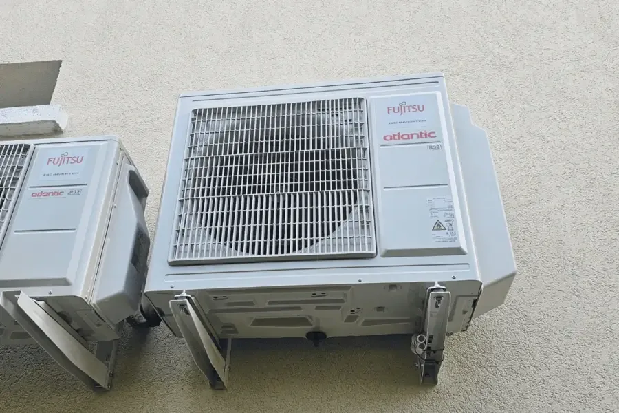 Deux unités extérieures de climatisation Fujitsu posées au sol sur leurs supports le long d’une façade