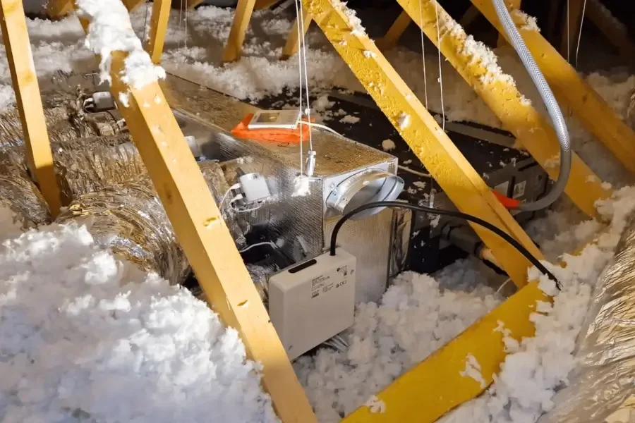 Caisson gainable d’une pompe à chaleur air-air suspendu dans des combles isolés, avec ses départs de gaines